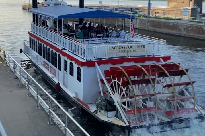 Paddlewheel riverboat named 'LaCrosse Queen VII' navigating through a lock.